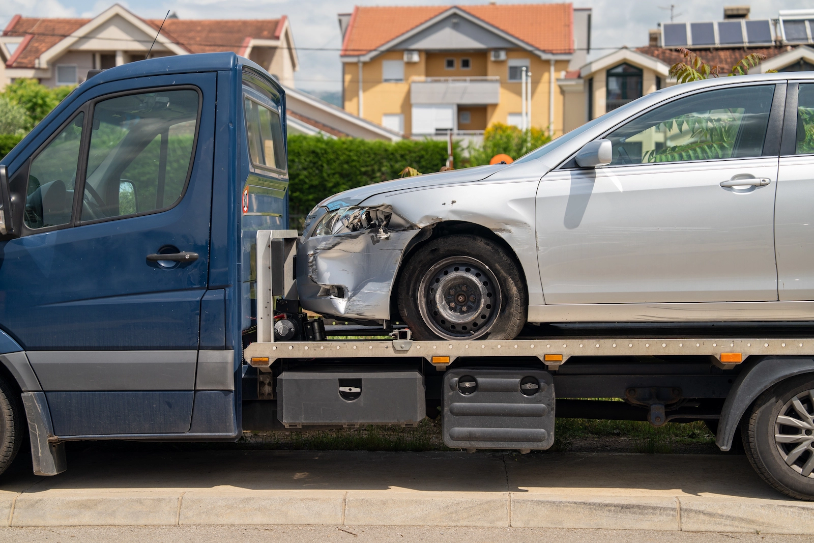 Damaged car being transported on a tow truck, representing comprehensive auto insurance coverage for unexpected incidents.