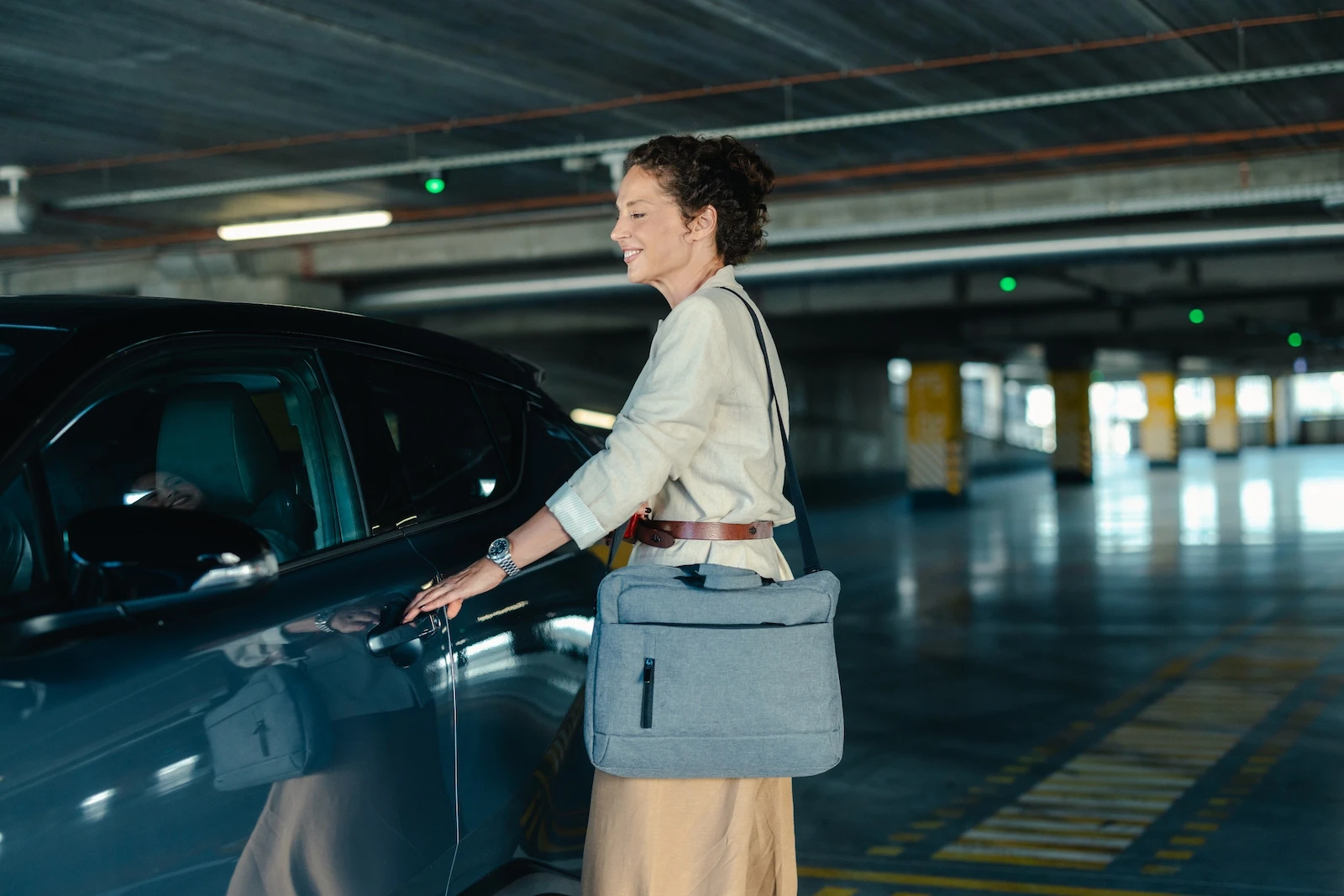Professional woman opening her car door with a laptop bag, representing auto insurance for daily commuters.
