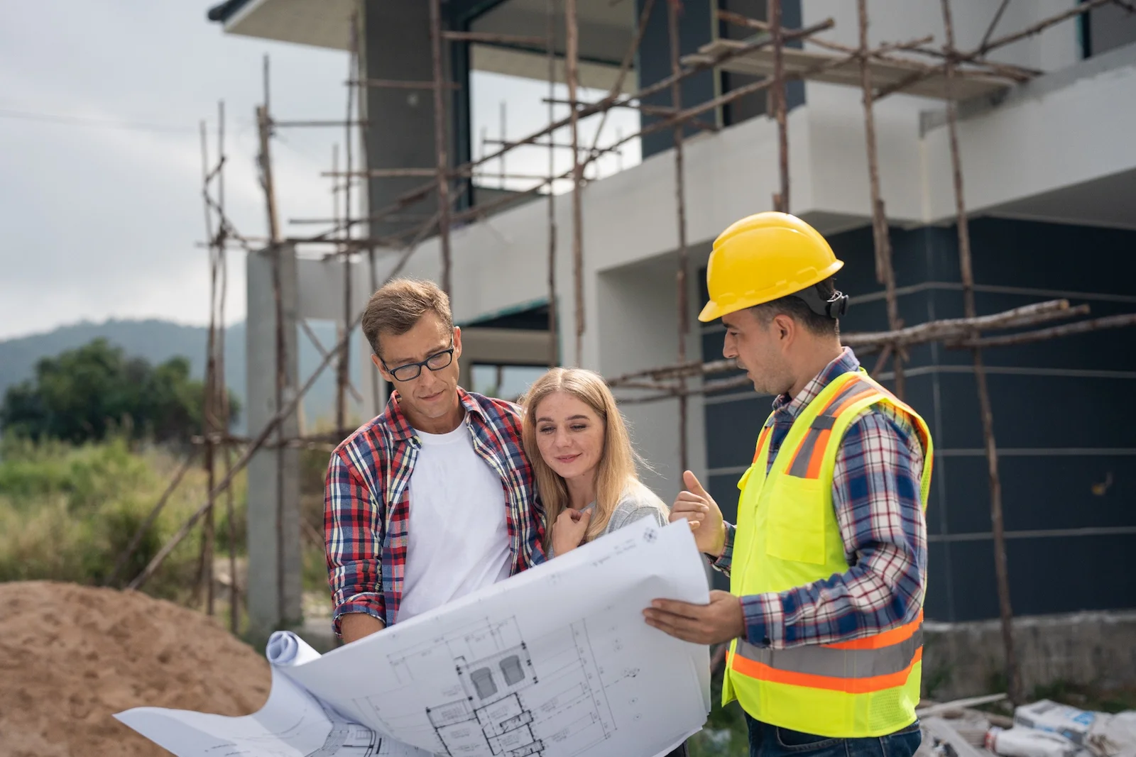 Homeowners reviewing construction plans with a builder at a residential construction site, representing builder’s risk insurance coverage for homes under construction.