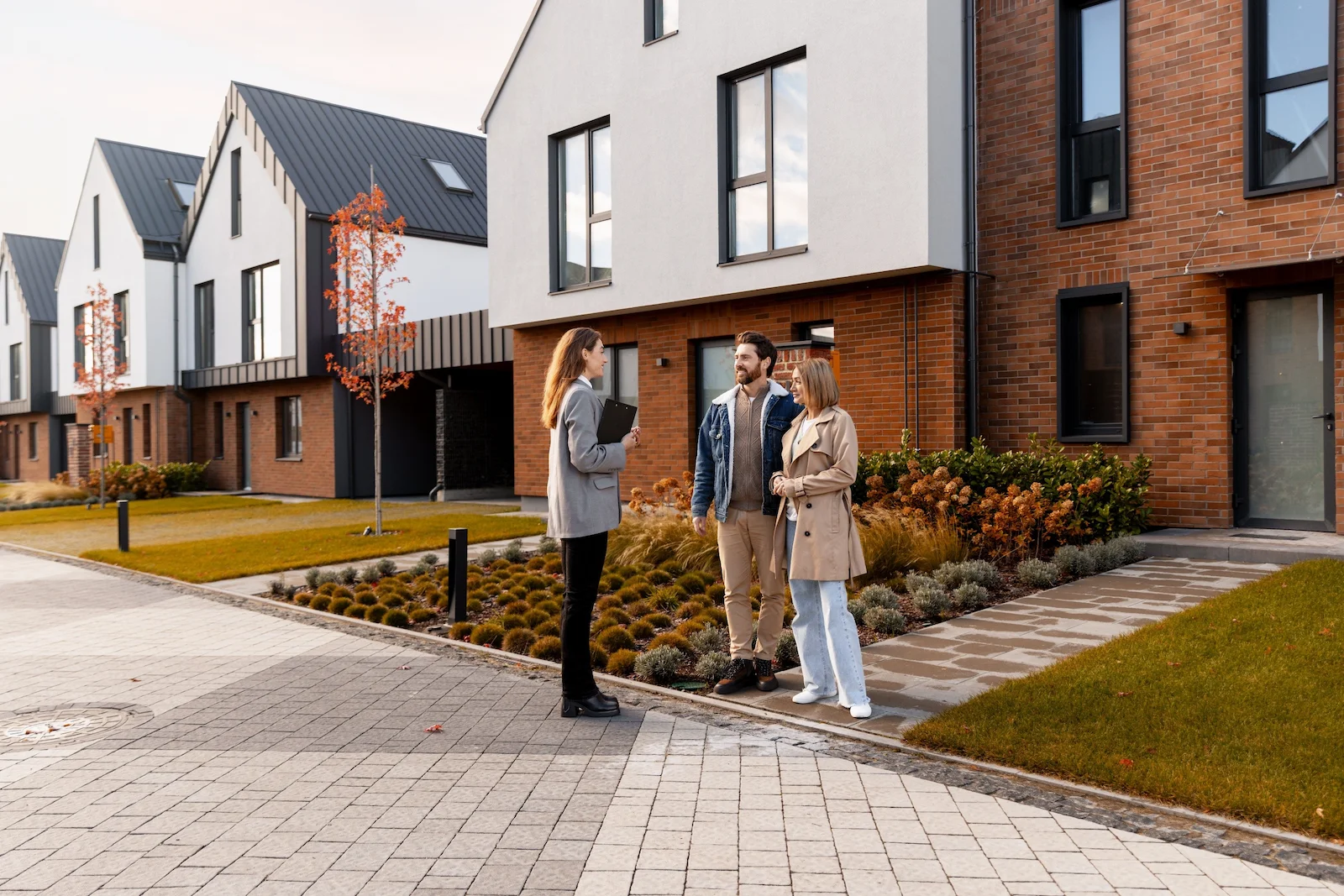 Couple touring a modern townhome community with a housing professional, representing homeowners insurance coverage for condo and townhome owners.