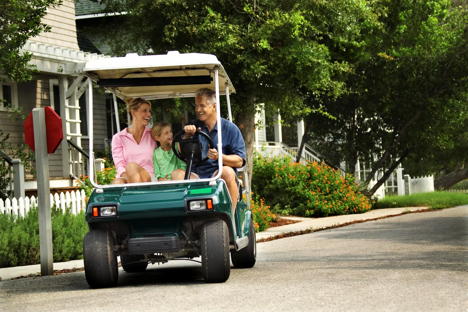 Family riding a golf cart through a residential community, representing recreational vehicle insurance coverage for additional recreational vehicles.