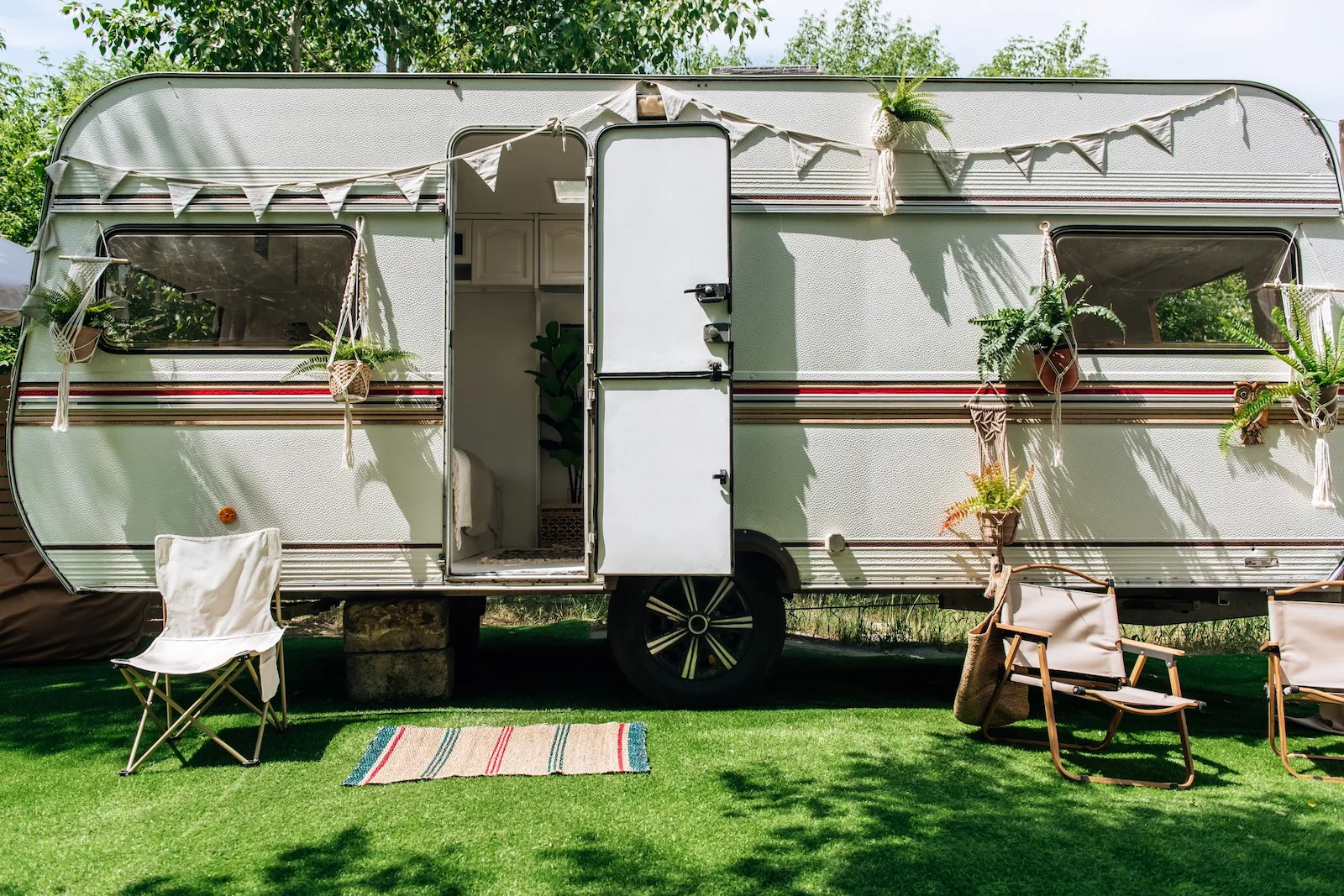 Travel trailer set up at a campsite with outdoor seating, representing recreational vehicle insurance coverage for travel trailers and campers.