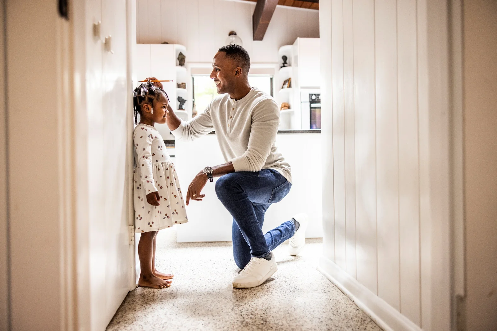 Parent measuring a child’s height inside a home, representing umbrella insurance protection for individuals with growing assets and financial responsibilities.