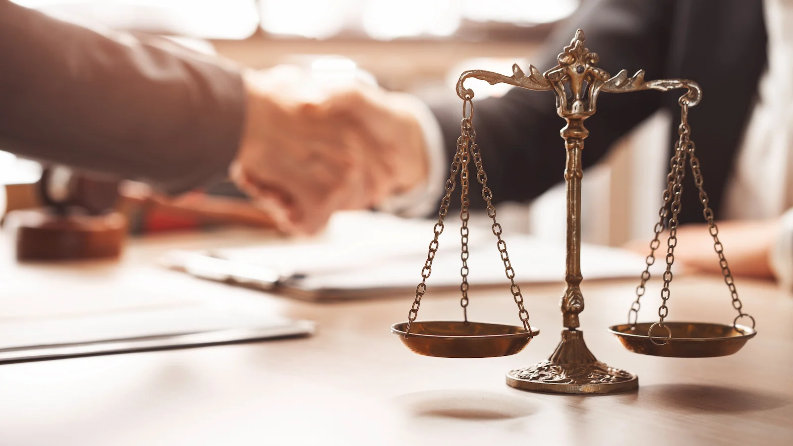 Scales of justice in a legal office with professionals reviewing documents, representing umbrella insurance coverage for legal defense costs.