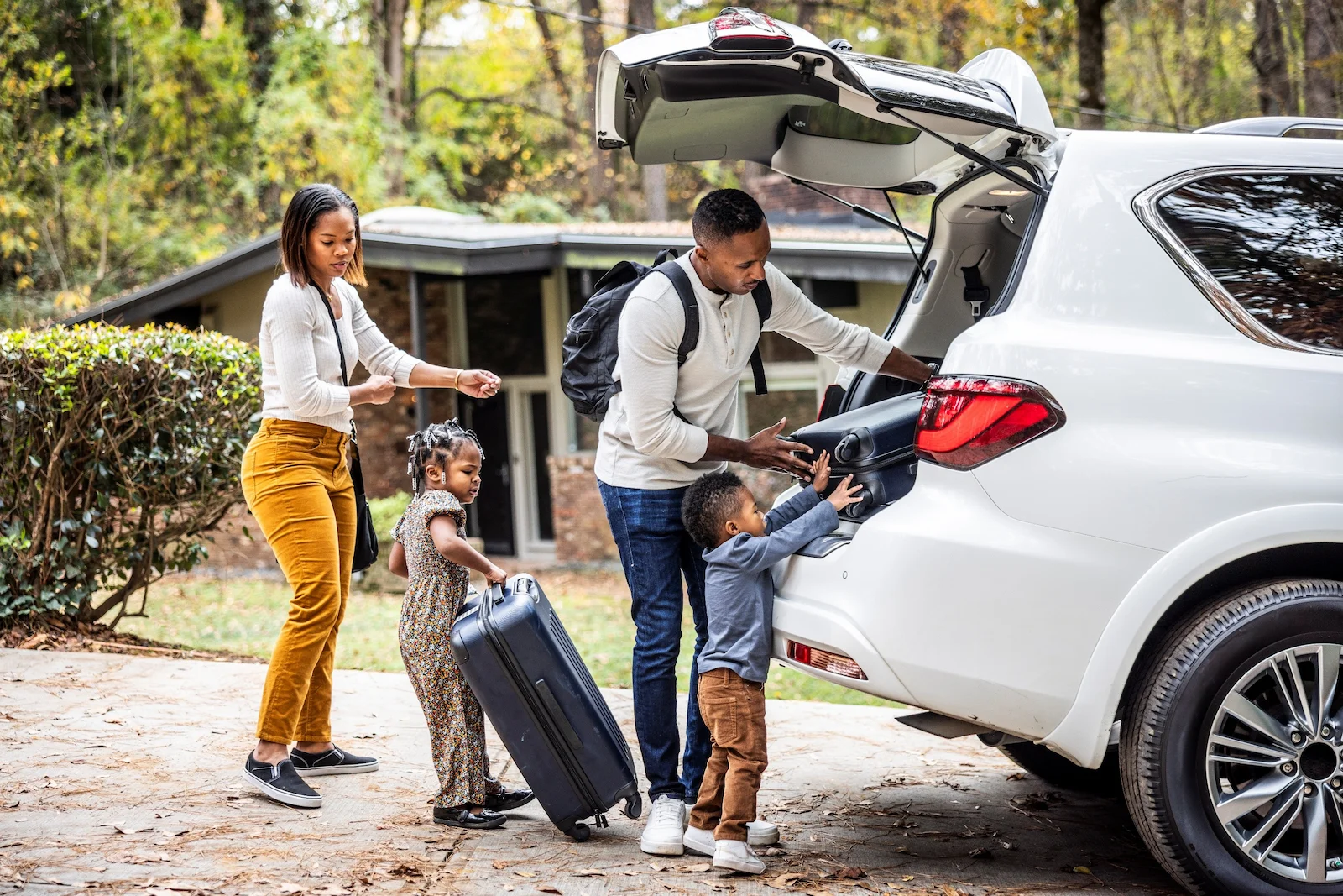 Family loading suitcases into a car for a trip, representing umbrella insurance protection for lifestyle and personal assets.