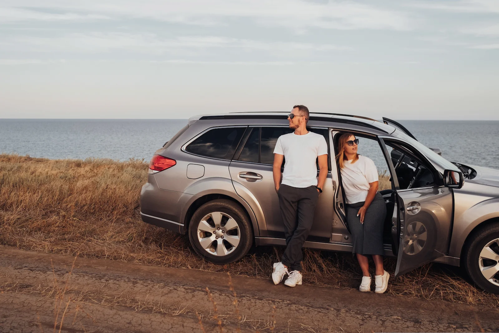 Couple standing beside an SUV near the coastline, representing umbrella insurance protection for vehicle owners and extended liability coverage.