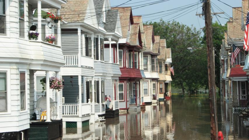 Flooded residential street with rows of homes surrounded by water, highlighting the need for flood insurance coverage.